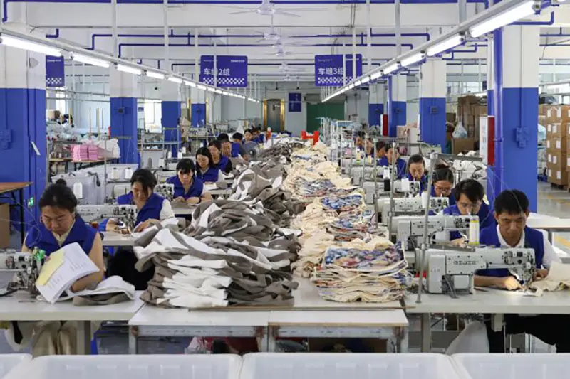 Workers sewing garment pieces across the production floor