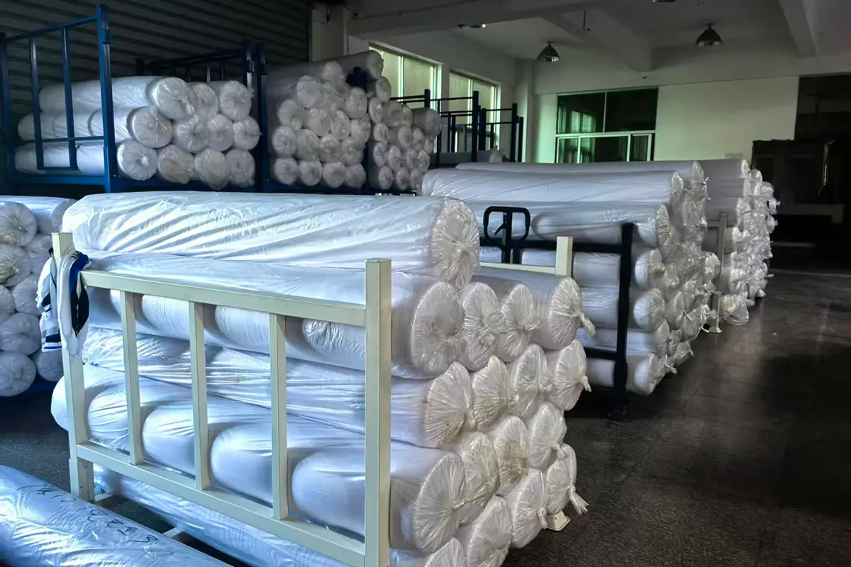 White fabric rolls stored in metal warehouse racks
