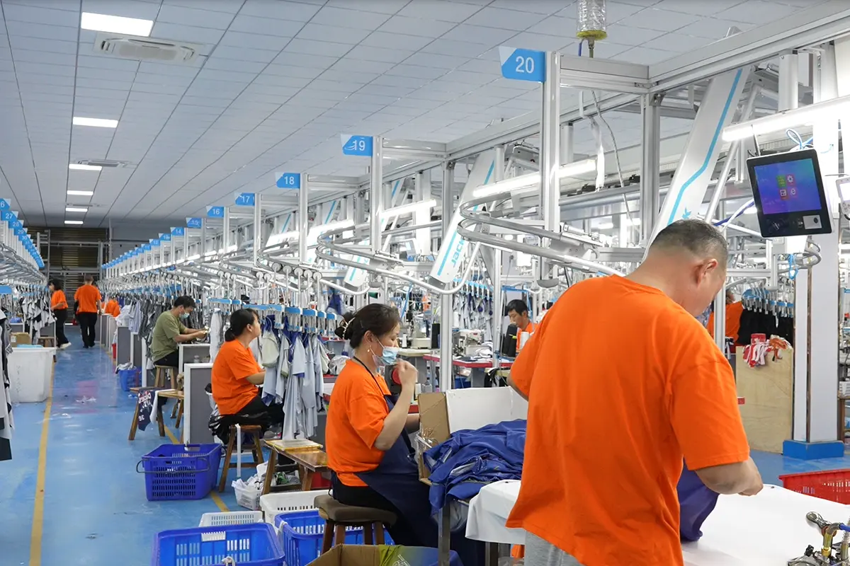 Workers sewing jersey pieces at numbered production stations