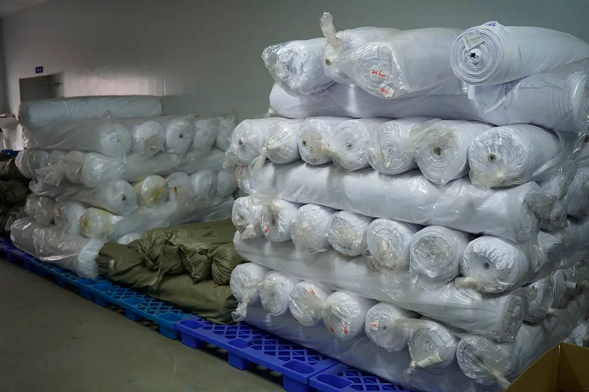 White fabric rolls stacked on pallets in the material store