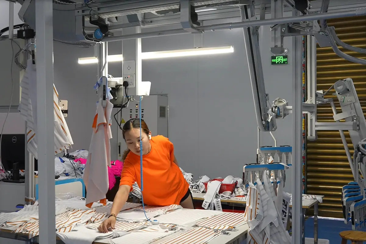 Worker checking printed jersey panels at a production station