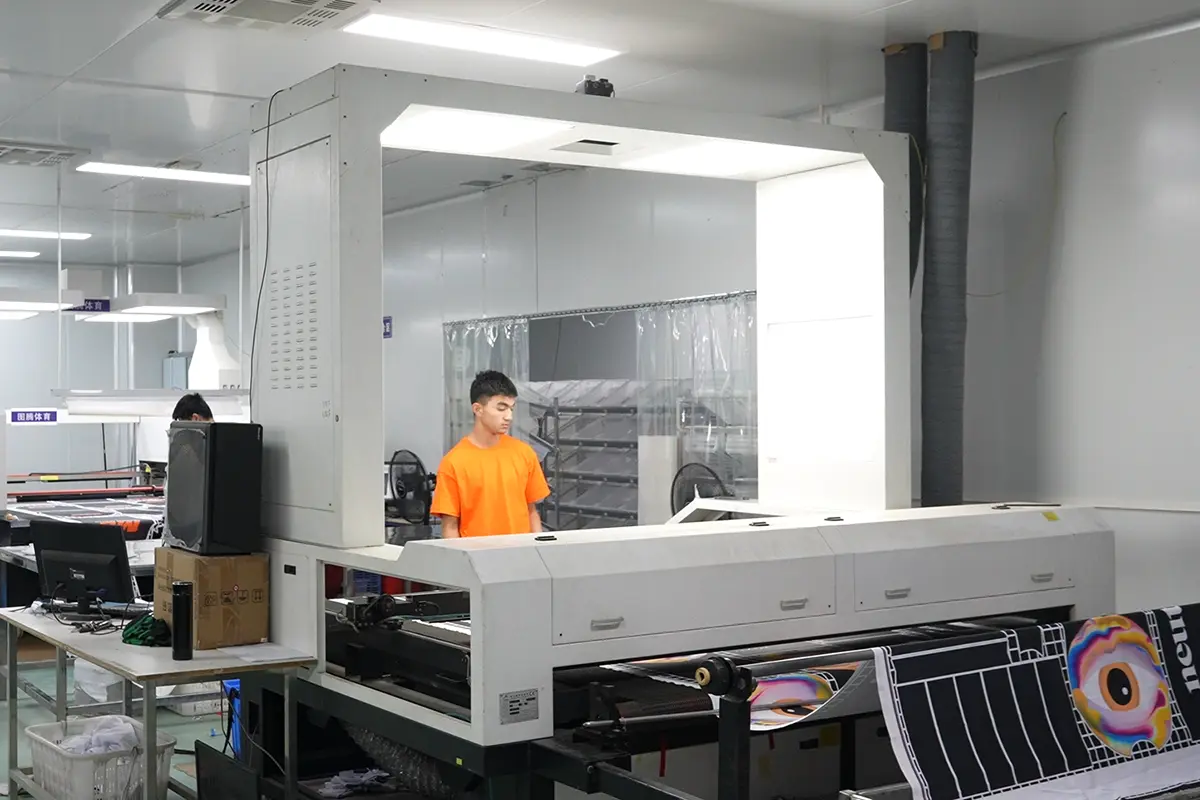 Operator monitoring patterned jersey panels at a printing station