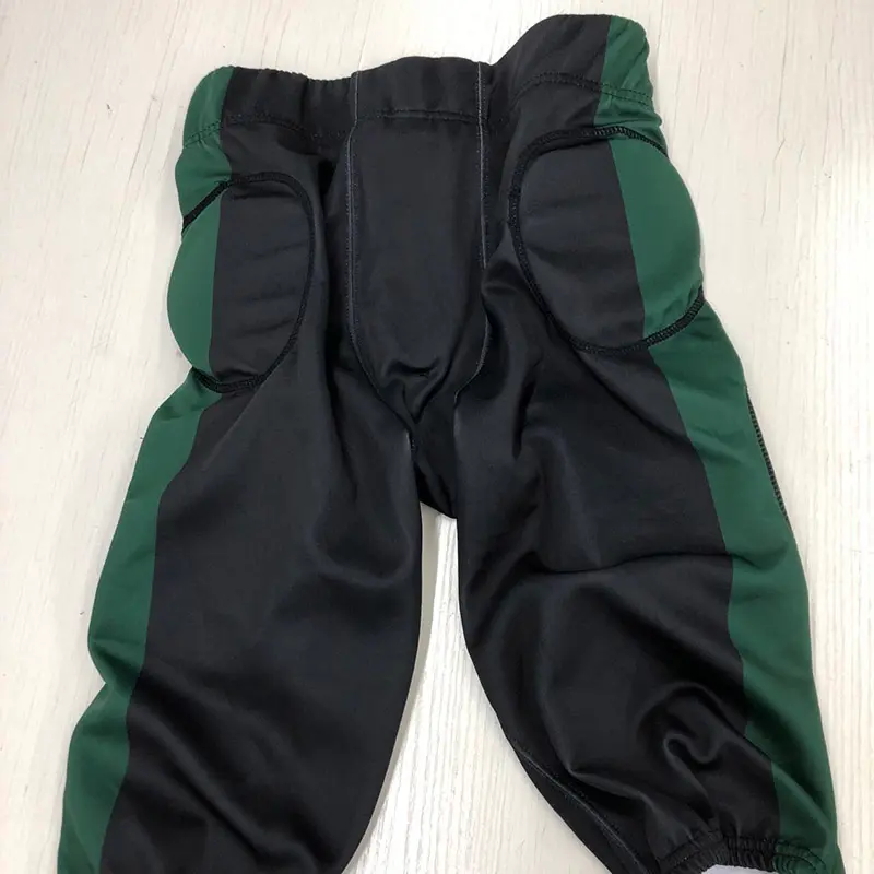 Black and green padded American football pants laid flat