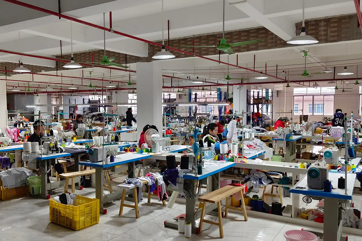 Workers sewing teamwear across a production floor