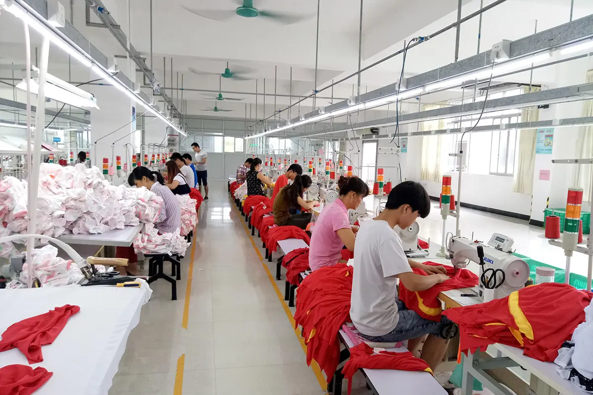 Workers sewing red and yellow jerseys along a production line