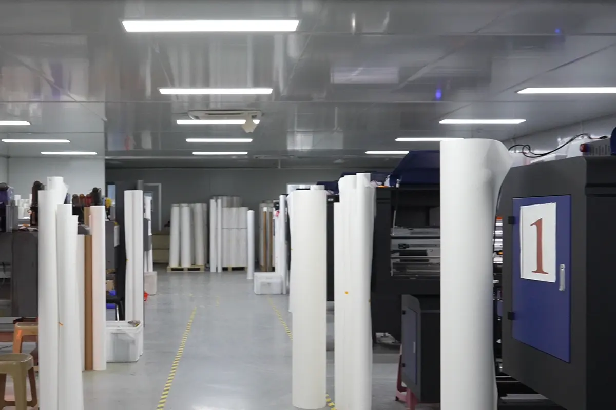 White material rolls standing beside wide-format printing machines