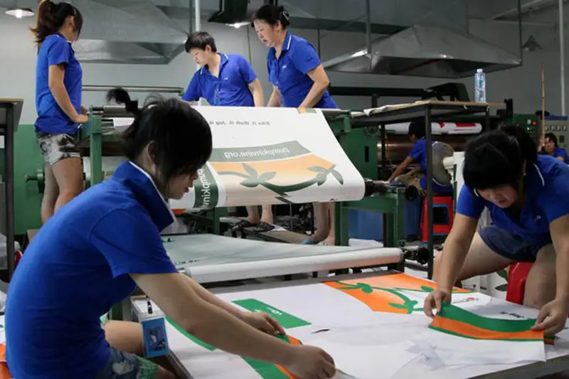 Workers aligning printed panels at a production table