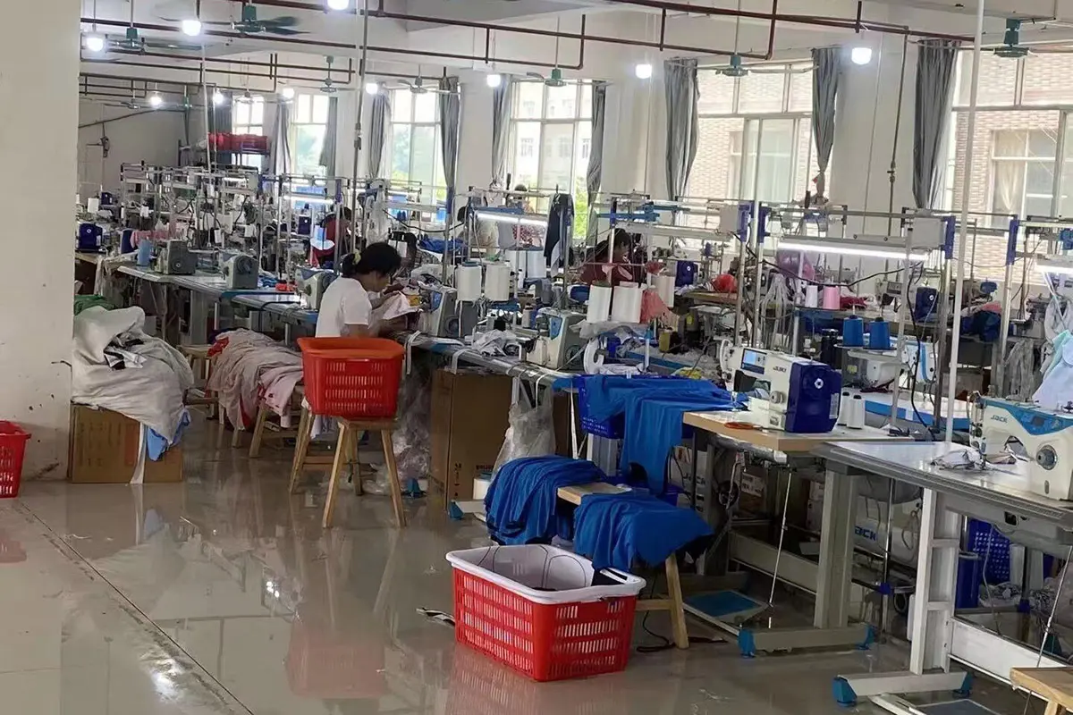 Blue jerseys sorted beside red work baskets on the sewing floor