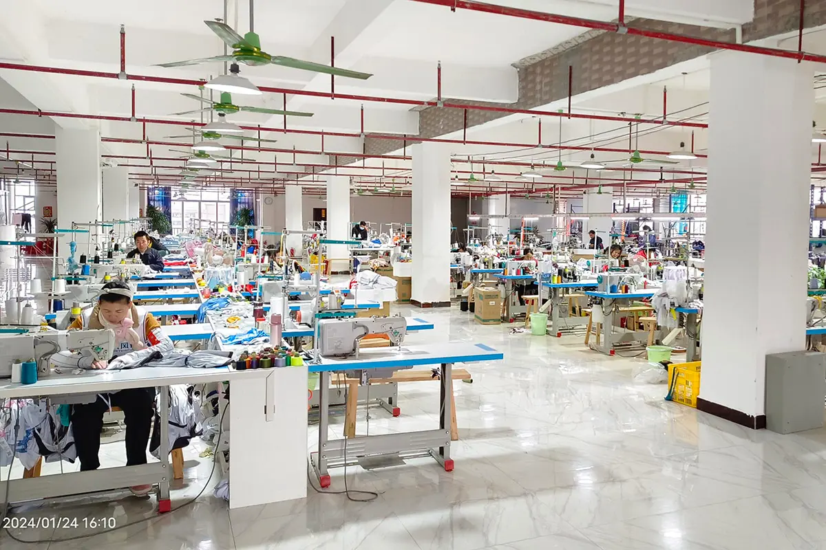 Workers sewing jerseys across a bright production workshop