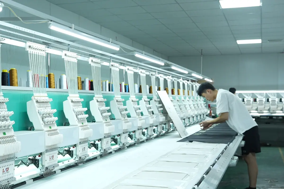 Worker aligning fabric on a multihead embroidery machine