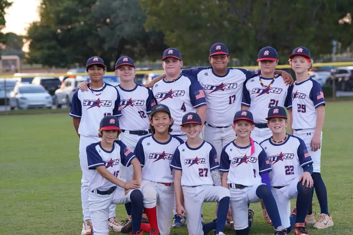 Youth baseball team wearing matching white and navy jerseys at the field