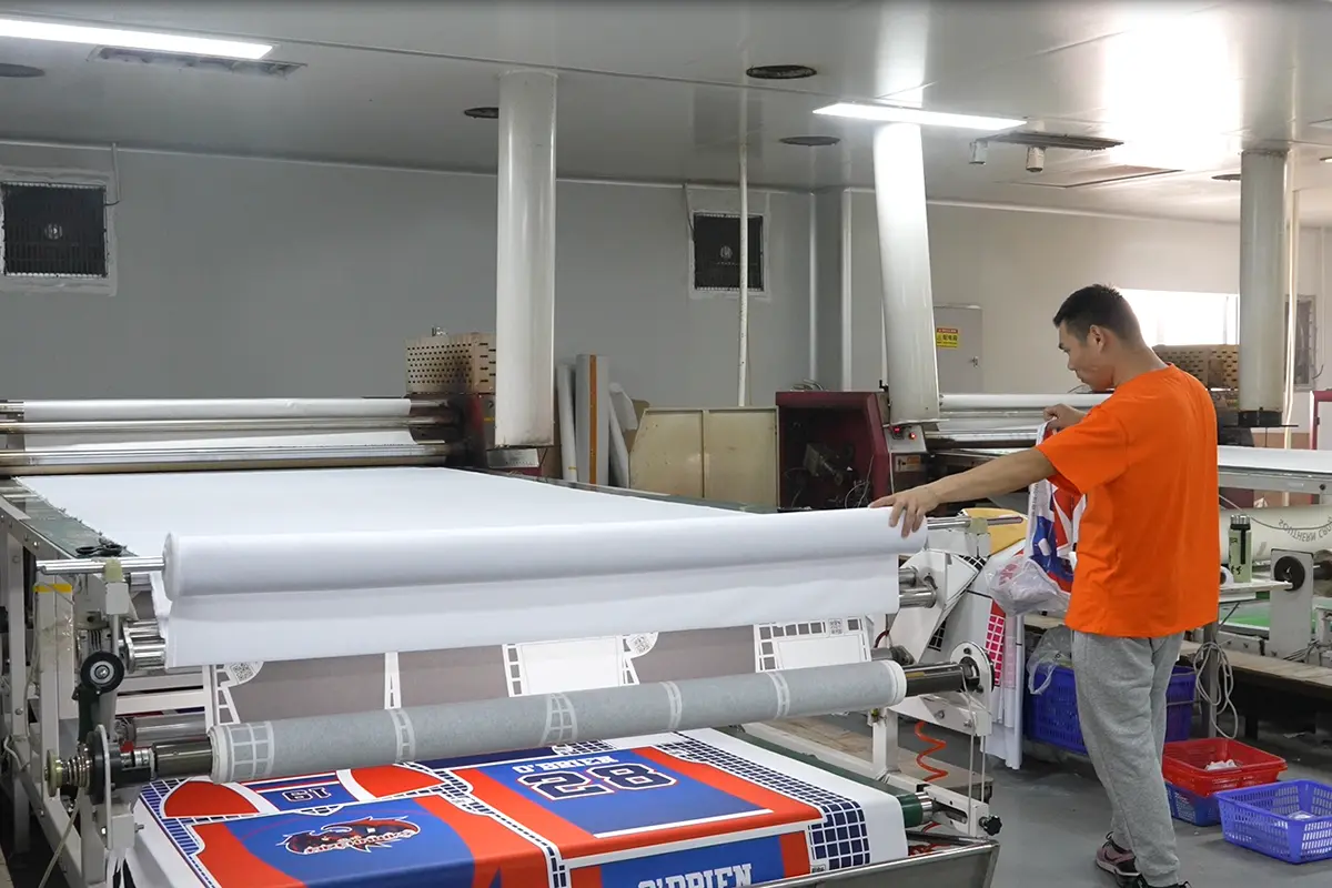Operator feeding printed jersey panels through a roll heat press